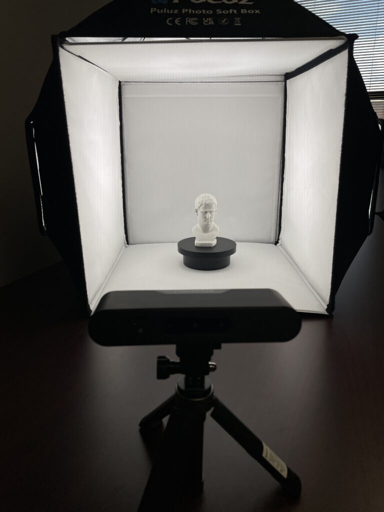 IMG_2538 camera-level view of a photo light box containing a white bust of an ancient figure on a black turntable
